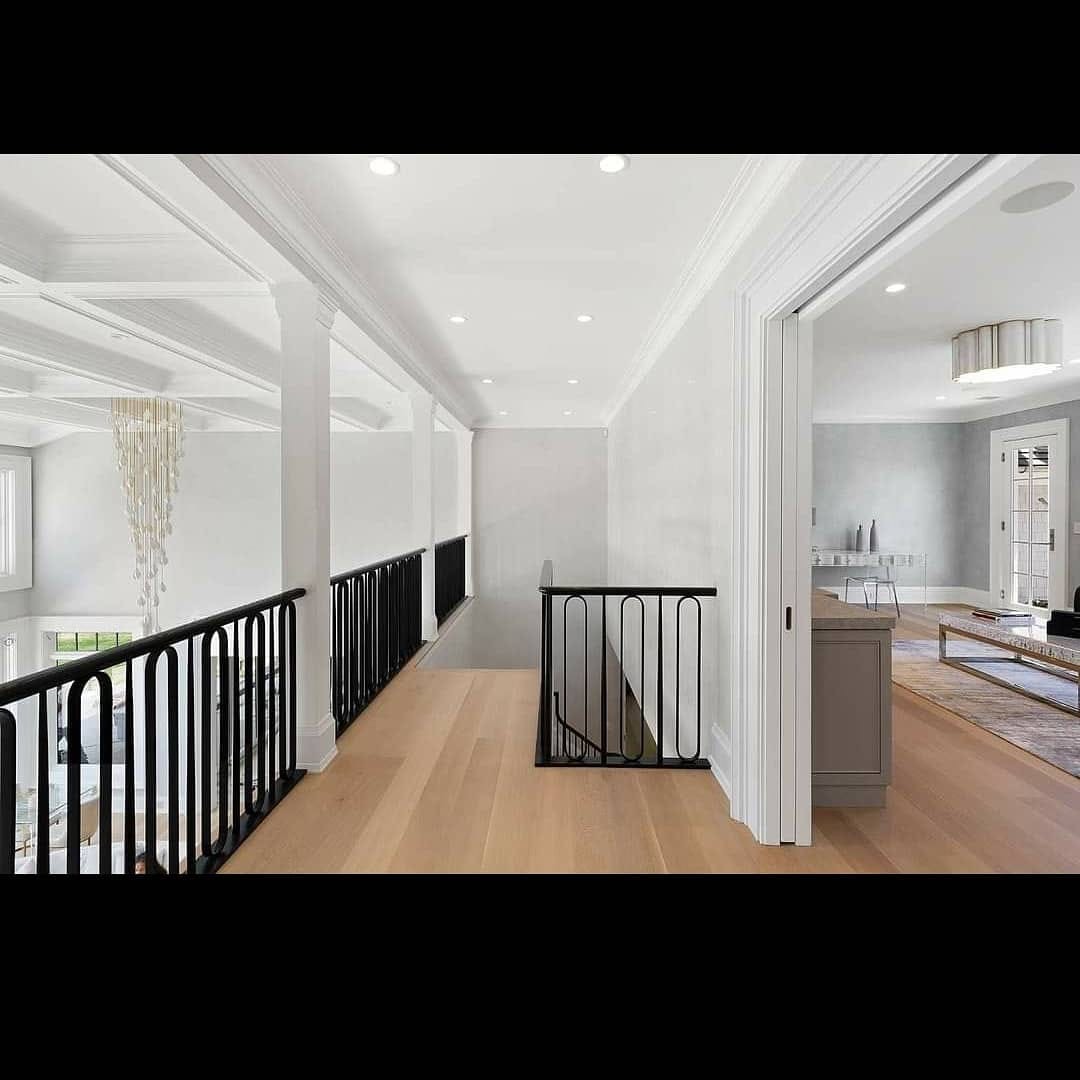 Bright painted upper hallway with detailed trim and black railings
