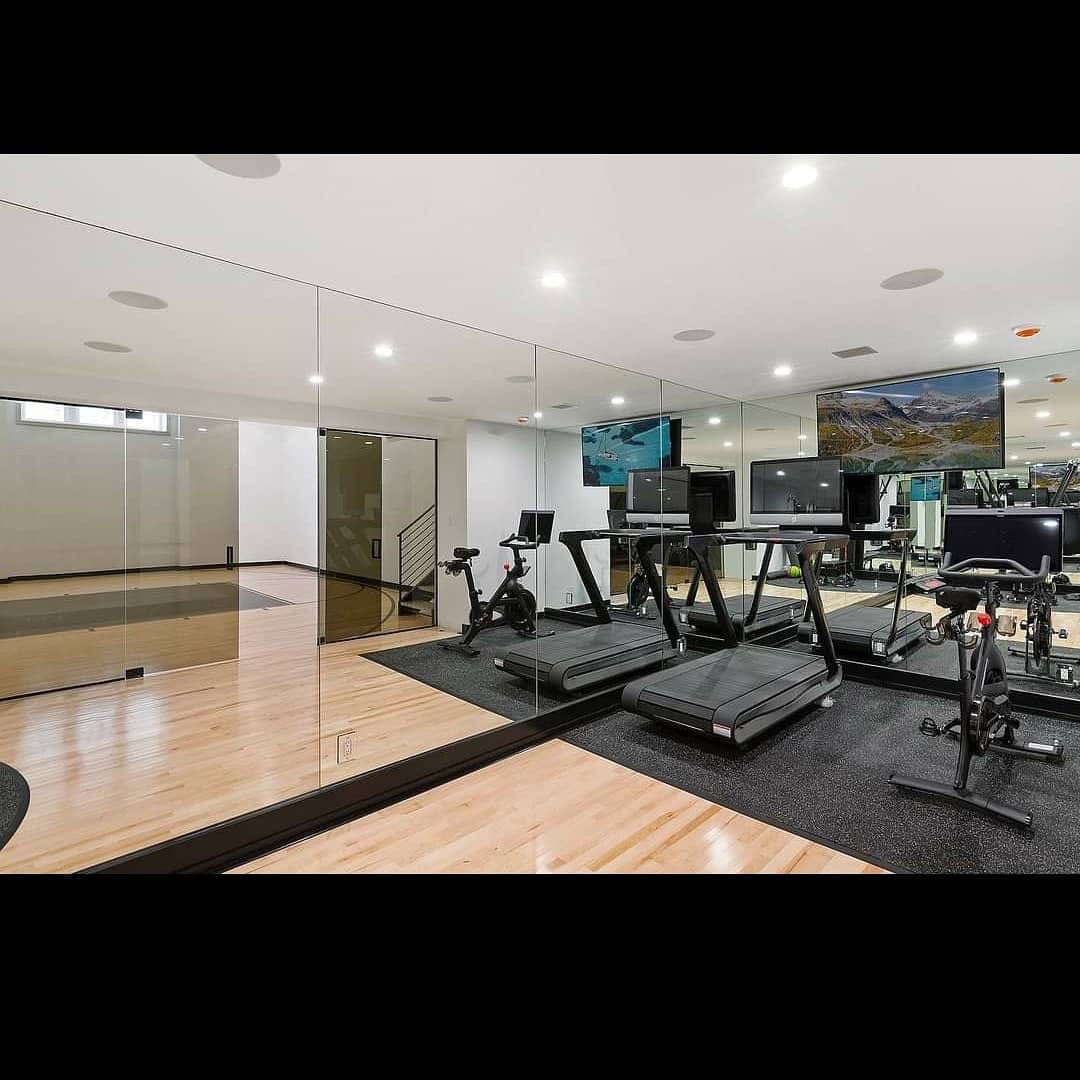 Finished home gym with mirrored walls and bright white ceiling
