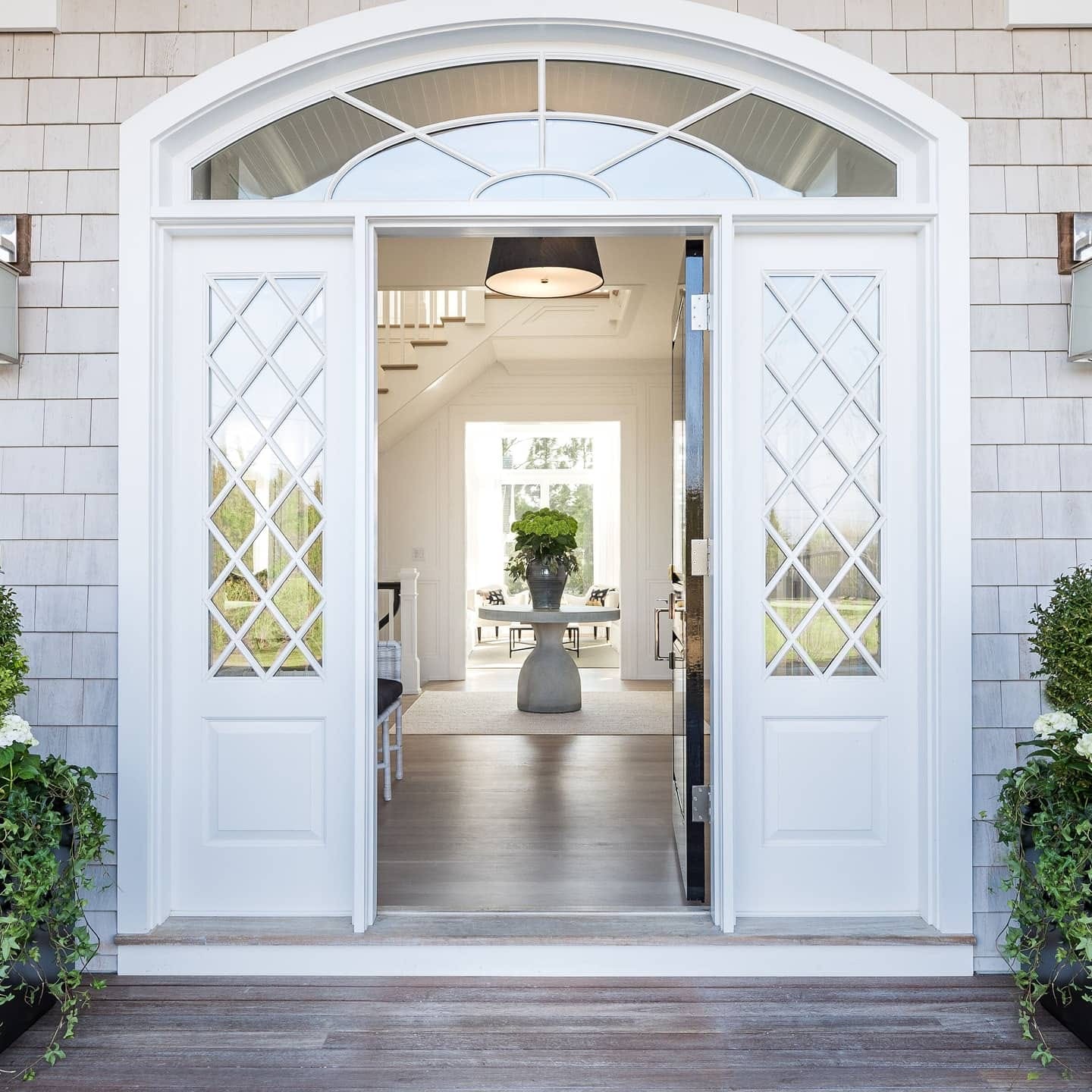 Grand front entry with double doors, diamond-paned glass, and arched transom, freshly painted in bright white
