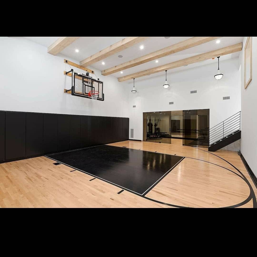 Finished indoor basketball court with white walls and exposed wood beams