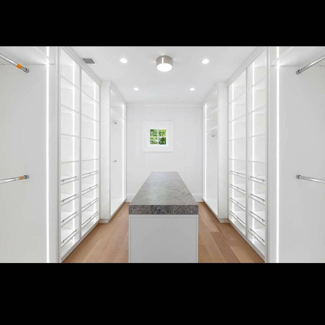 Finished walk-in closet with bright white shelving and wood floor