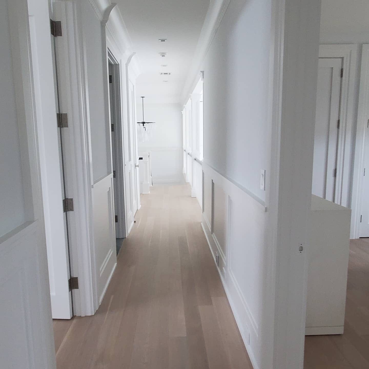 Bright white hallway with wainscoting, panel details, and crisp trim